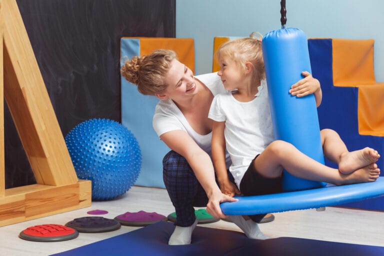 Dziecko podczas terapii integracji sensorycznej z terapeutką w sali Domisiowej Chatki – terapia integracji sensorycznej wspiera rozwój dziecka przez ruch i zabawę.